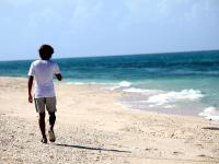 南国のビーチを歩く男性